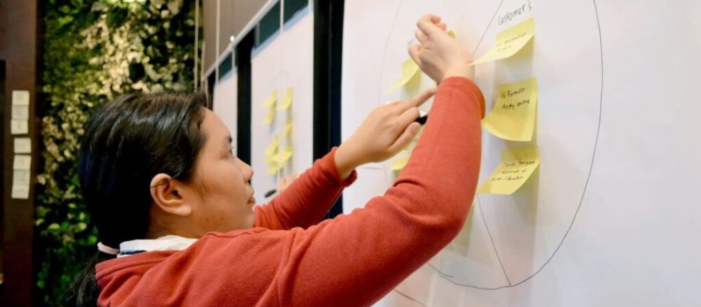 Woman sticking postate notes on a whiteboard